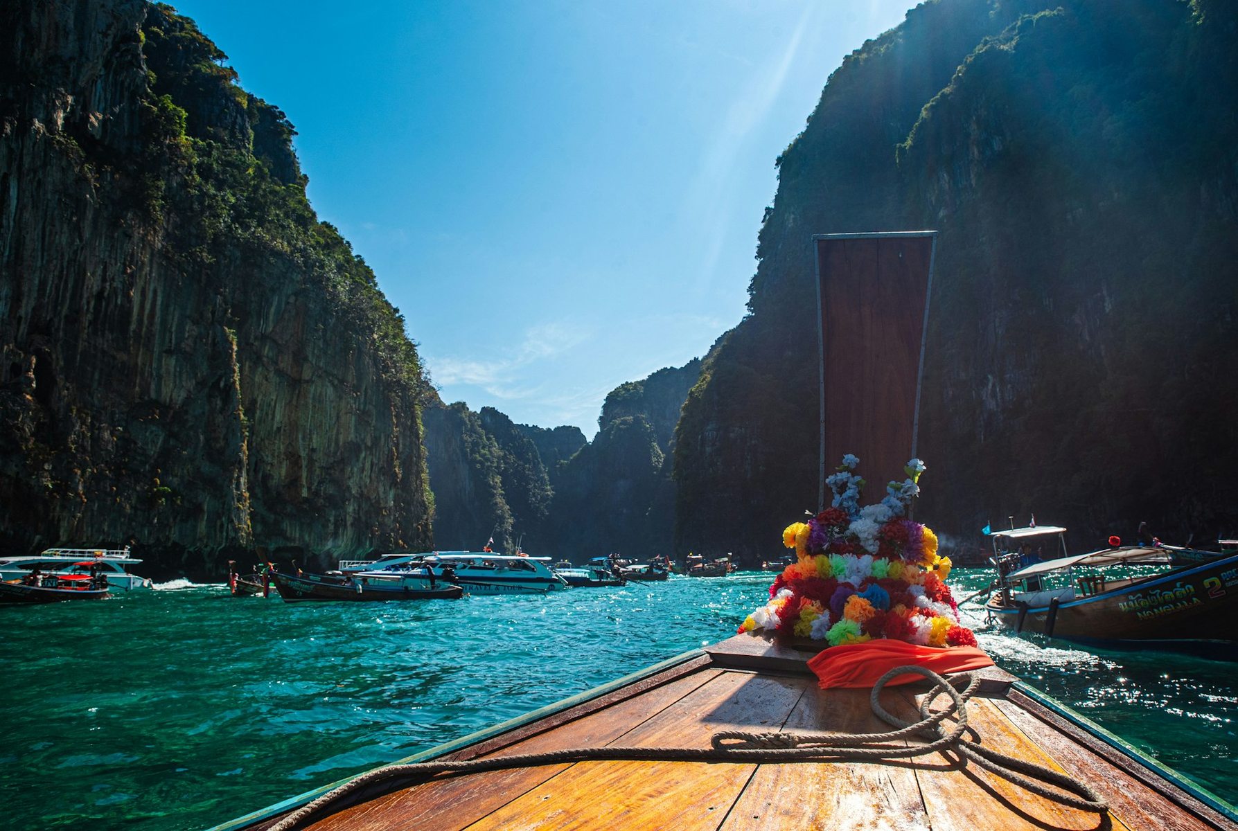A longtail boat on turquoise water between the limestone cliffs of Thailand